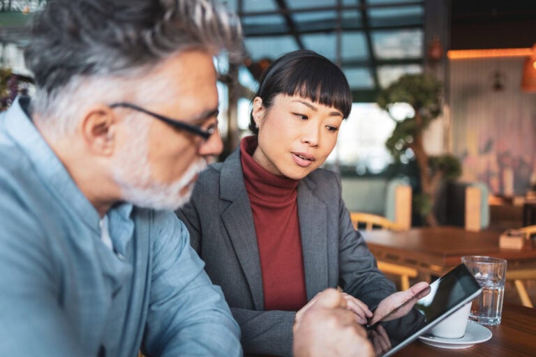Zwei Geschäftsleute bei IT-Beratung im Café, Nutzung eines Tablets